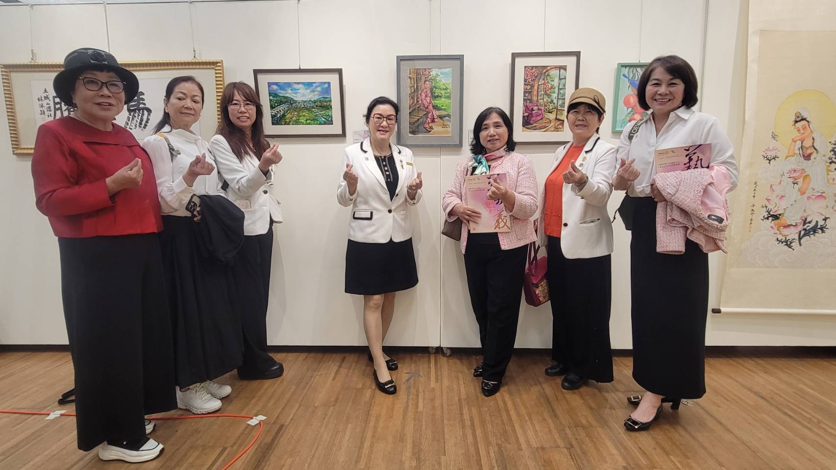 從畫室走向社會，藝術家、學界、學童齊聚　一場跨世代的愛心接力，參與社友在自己的作品前留念。